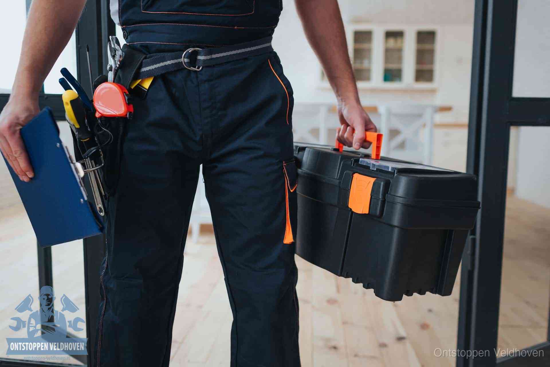 Een monteur met gereedschapsriem en klembord in een keuken, klaar om een transparante prijs voor het gootsteen ontstoppen in Veldhoven te geven