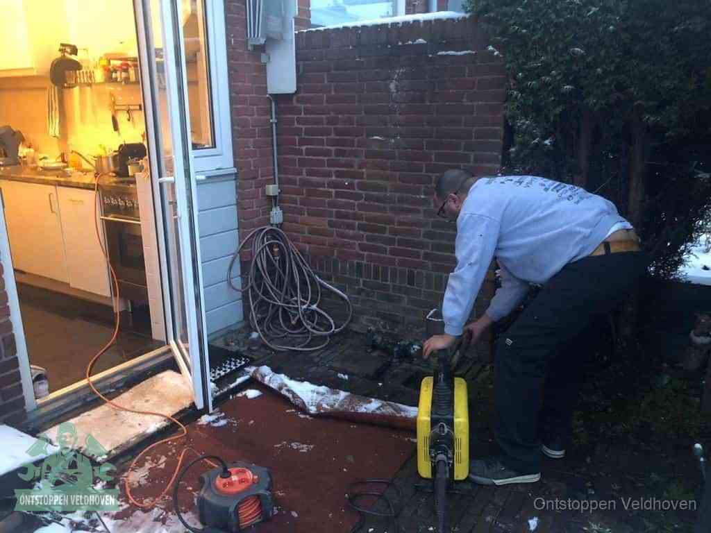 Een monteur werkt buiten bij een open riool-/grondput met een elektrische ontstoppingsmachine om een verborgen afvoerprobleem op te sporen in Veldhoven