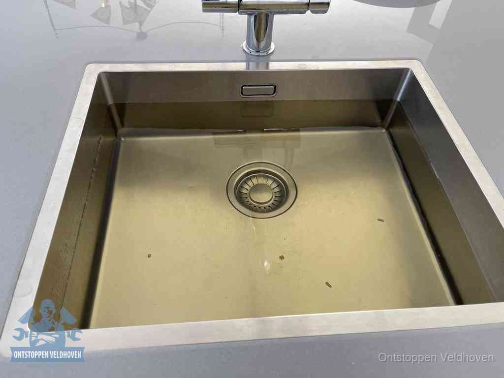Stilstaand water in een rvs spoelbak dat niet wegloopt, een duidelijk signaal van een gootsteenverstopping in Veldhoven