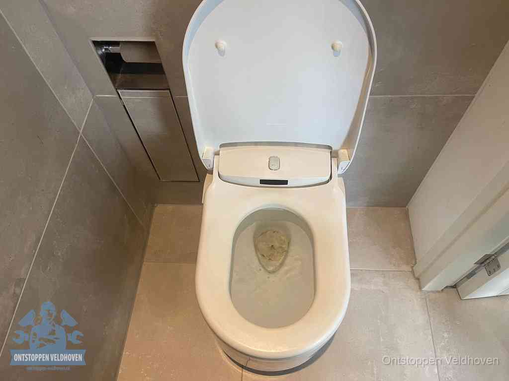 Een wit hangtoilet waarin een prop wc-papier op het water blijft drijven, een duidelijk signaal van een verstopte wc in Veldhoven