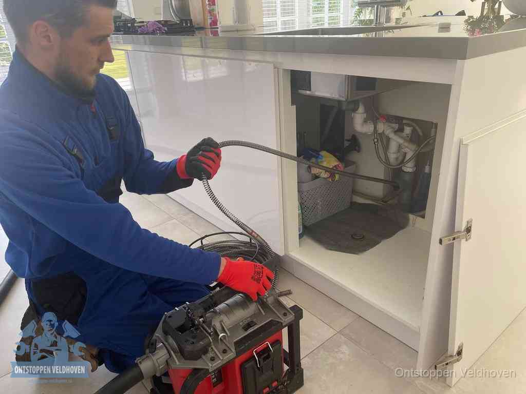Een monteur reinigt de keukenafvoer grondig met een veermachine om terugkerende gootsteenverstoppingen te voorkomen in Veldhoven