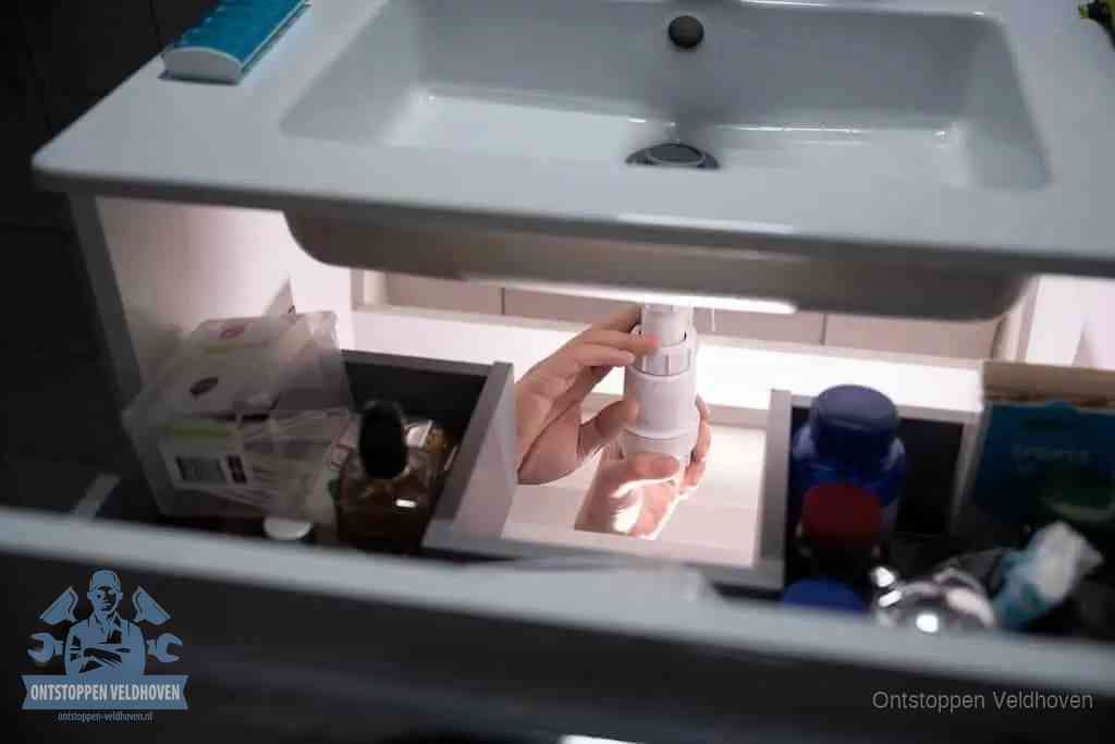Een pompfles met zeep boven een wastafel in de toiletruimte, de warm water en afwasmiddel-methode om de wc te ontstoppen in Veldhoven