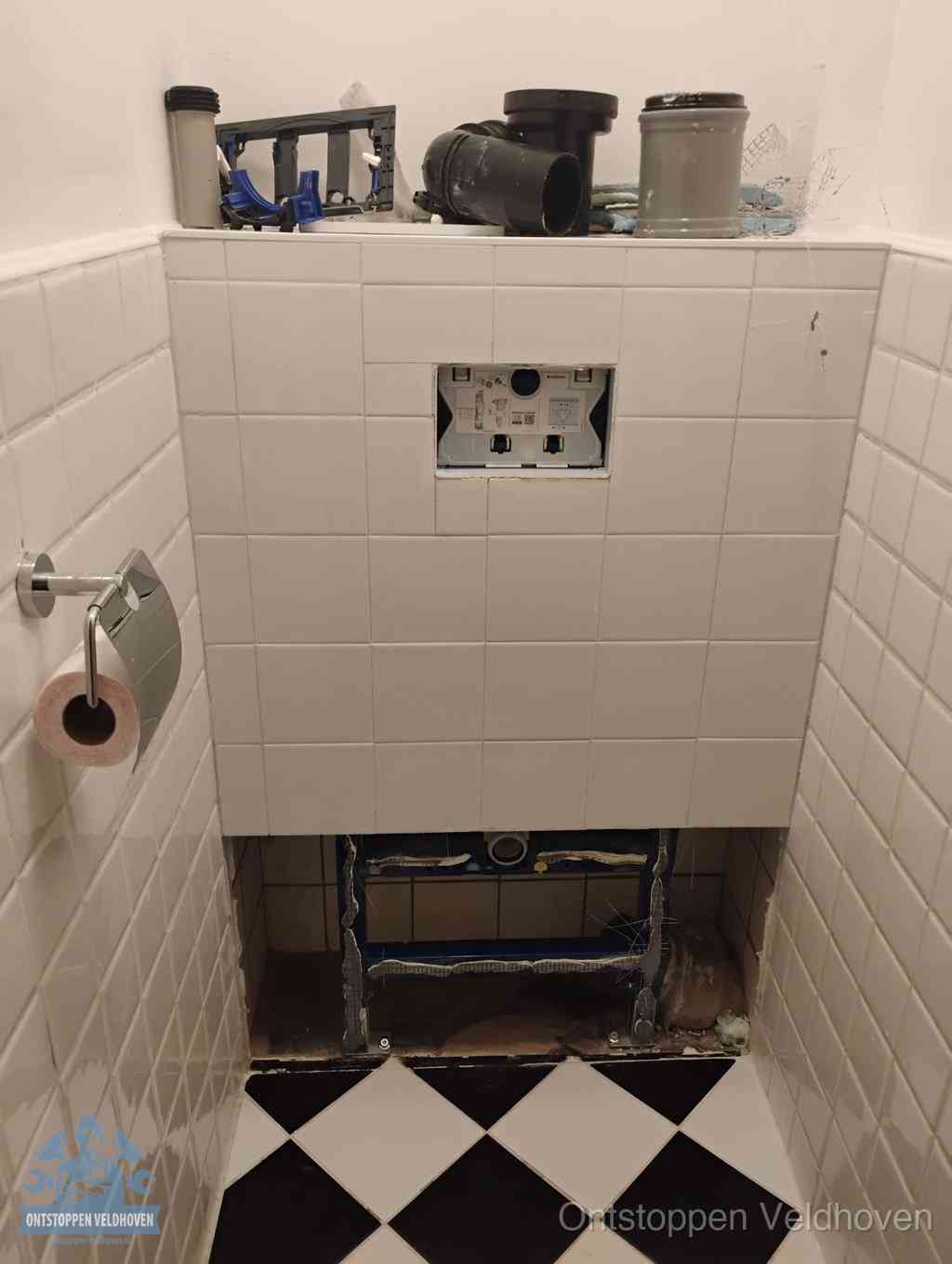 Een toiletruimte waar het hangtoilet en de inbouwreservoir-onderdelen zijn vrijgelegd voor onderhoud, periodiek nazicht voorkomt een wc-verstopping in Veldhoven